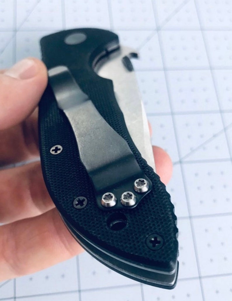 May include: Black pocket knife with a silver clip and a textured black handle. The knife has a silver blade and a silver pocket clip.