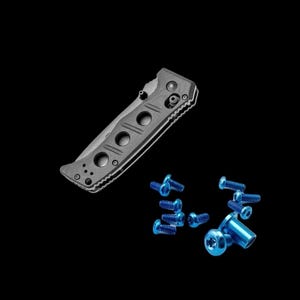 Peut inclure: Un couteau de poche noir avec une poignée texturée et des vis bleues. Le couteau est fermé et la lame n'est pas visible.