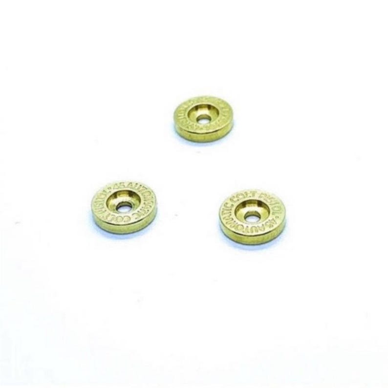 May include: Three gold-colored metal discs with the words "COLT AUTOMATIC" and "COLT REVOLVER" engraved around the edges.