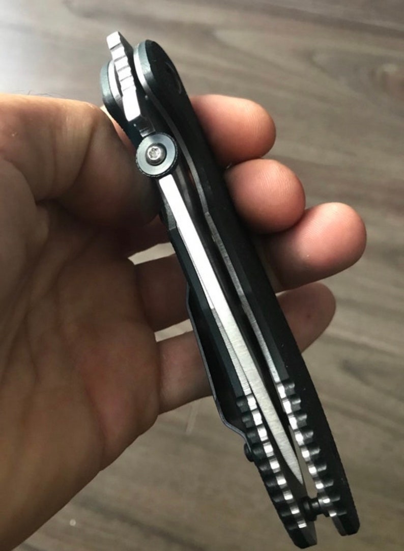 May include: A black folding knife with a silver blade and a textured handle. The knife is partially open, showing the blade and the mechanism.