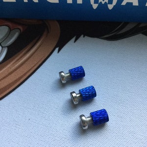 Könnte beinhalten: Drei blaue Metallschrauben mit silbernen Köpfen. Die Schrauben sind in einer Reihe von links nach rechts angeordnet, wobei die Schraube links die größte und die Schraube rechts die kleinste ist.