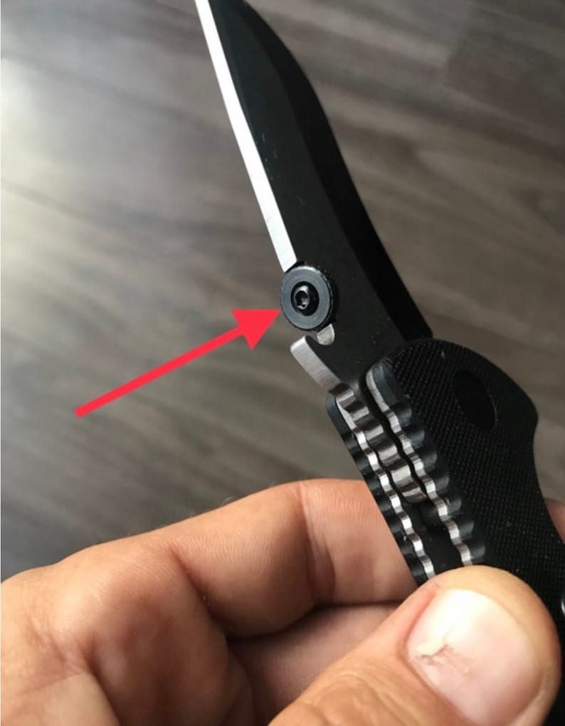 May include: Close-up of a black pocket knife with a silver blade and a textured black handle. A silver screw is visible on the side of the knife.