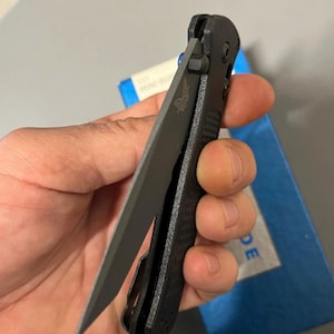 Könnte beinhalten: Ein schwarzes Klappmesser mit einer teilweise geöffneten Klinge. Die Klinge ist aus grauem Metall und trägt die Gravur "Spyderco". Der Griff ist aus schwarzem, strukturiertem Kunststoff.