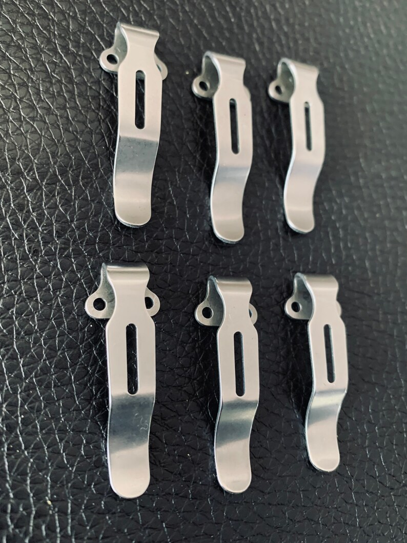 K&ouml;nnte beinhalten: Sechs silberne G&uuml;rtelschnallen aus Metall mit gebogenem Design und einem kleinen Loch oben.