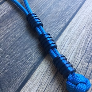May include: A blue paracord bracelet with black metal beads. The bracelet has a knot at the end.