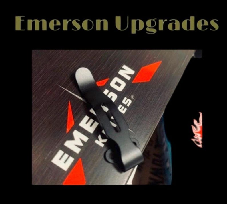 May include: A black pocket clip for a knife, with a silver top, is shown against a dark background. The text "Emerson Knives" is visible in white, with red diamond accents. The words "Emerson Upgrades" are at the top.