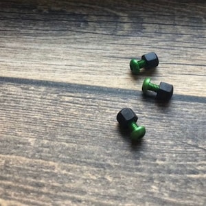 May include: Three black and green metal screws with hexagonal heads.