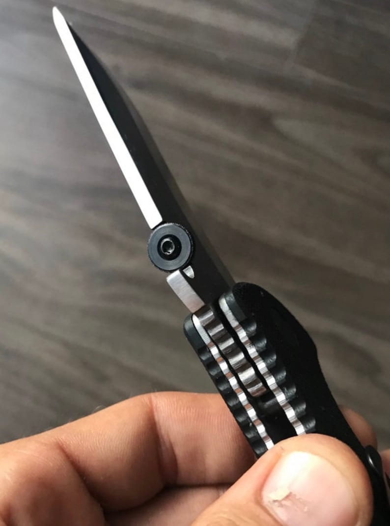 May include: A black folding knife with a partially extended blade. The knife has a black handle with a silver accent and a silver pivot screw.