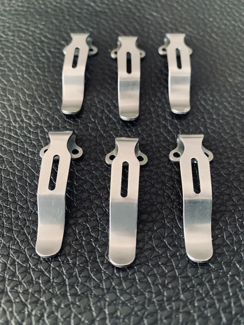 K&ouml;nnte beinhalten: Sechs silberne Metall-Taschenclips f&uuml;r ein Messer oder ein Multitool. Die Clips sind so konzipiert, dass sie an einem G&uuml;rtel oder einer Tasche befestigt werden k&ouml;nnen.