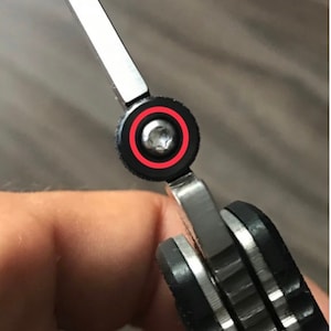 May include: Close-up of a silver pocket knife with a black handle. The knife is partially open, revealing a silver blade. A small screw is visible on the pivot point of the blade.