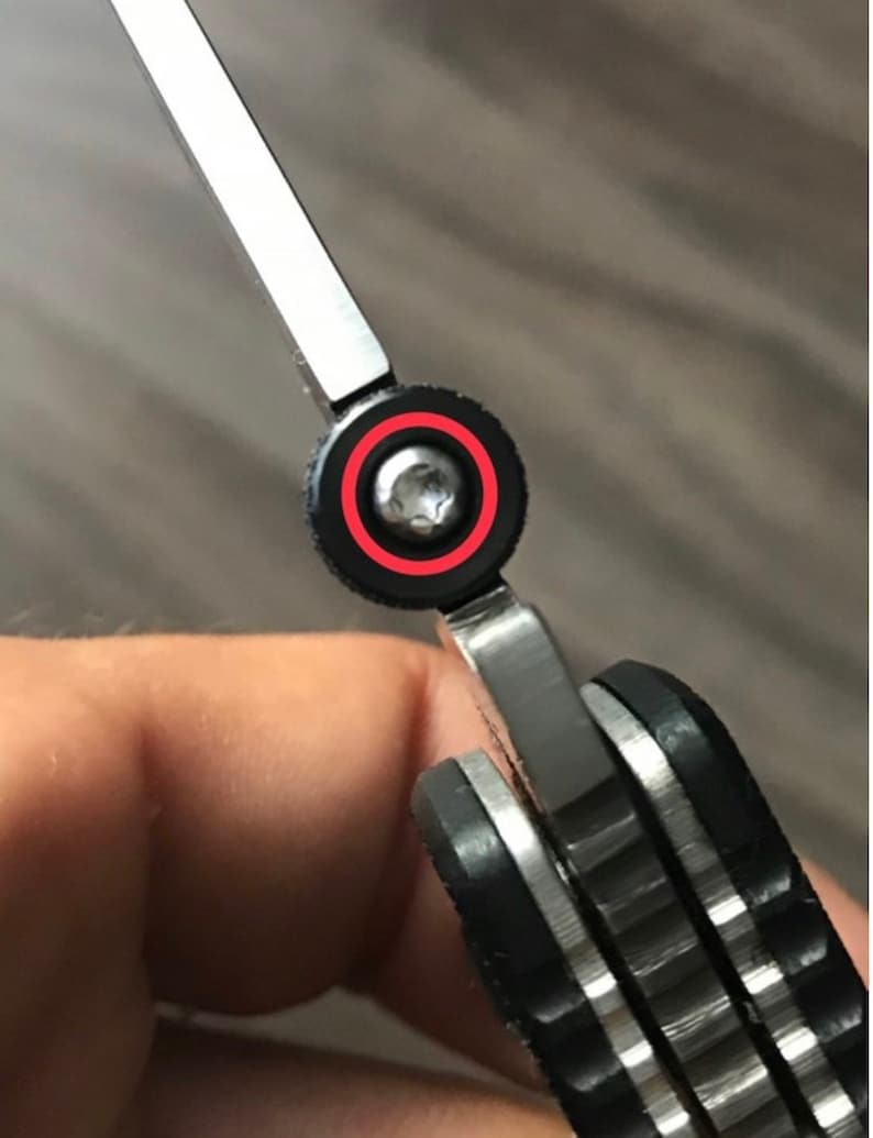 May include: Close-up of a silver pocket knife with a black handle. The knife is partially open, revealing a silver blade. A small screw is visible on the pivot point of the blade.