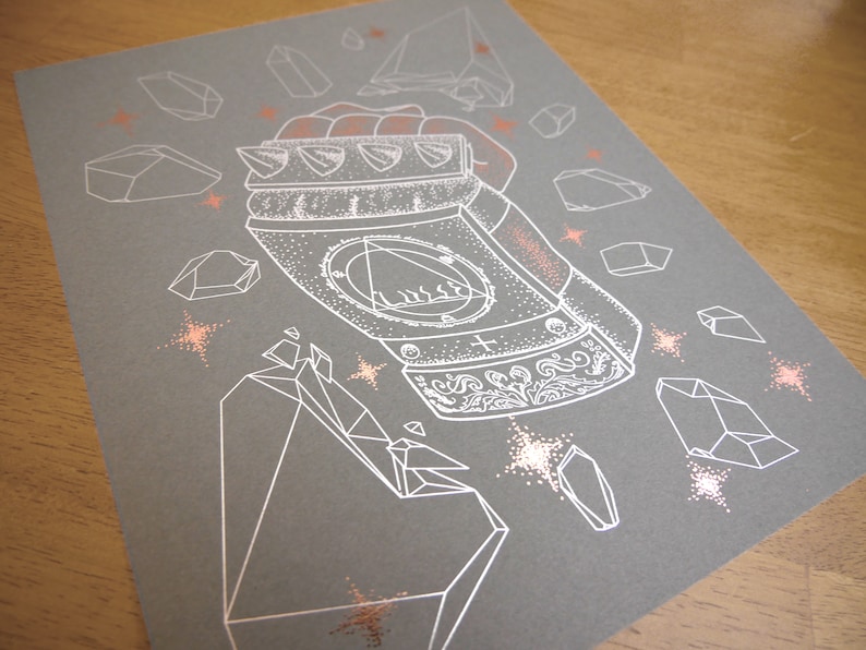 May include: A white line drawing of a metallic fist with a detailed design on a gray background. The fist is surrounded by white geometric shapes and small white stars. The background is a light gray color.