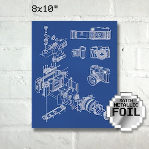 May include: A blueprint style illustration of a camera disassembled into its individual parts. The image is on a blue background with the text "8x10" in the top left corner. The text "SATIN METALLIC FOIL" is in a silver circle in the bottom right corner.