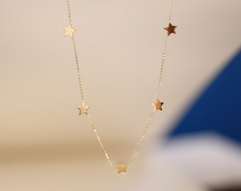 May include: A gold chain necklace with five small star charms.