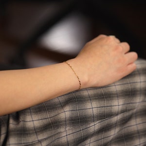 Puede incluir: Un delicado brazalete de cadena de oro con un patr&oacute;n de eslabones cuadrados.