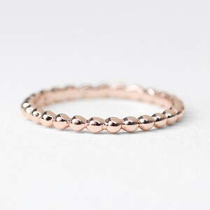K&ouml;nnte beinhalten: Ein zarter Ros&eacute;goldring mit einem Perlenmuster. Der Ring besteht aus kleinen, runden Perlen, die gleichm&auml;&szlig;ig auf der Band verteilt sind.
