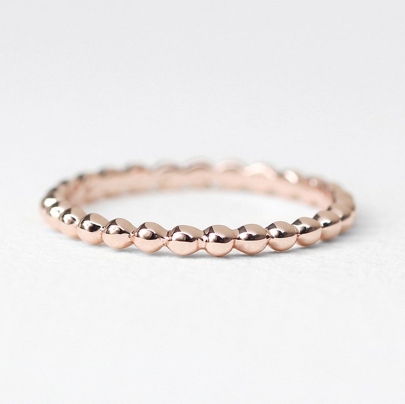 K&ouml;nnte beinhalten: Ein zarter Ros&eacute;goldring mit einem Perlenmuster. Der Ring besteht aus kleinen, runden Perlen, die gleichm&auml;&szlig;ig auf der Band verteilt sind.