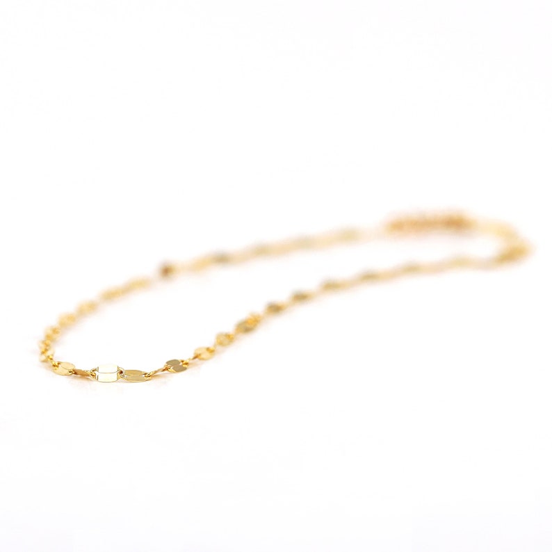 Puede incluir: Un delicado collar de cadena de oro con peque&ntilde;os eslabones ovalados planos.