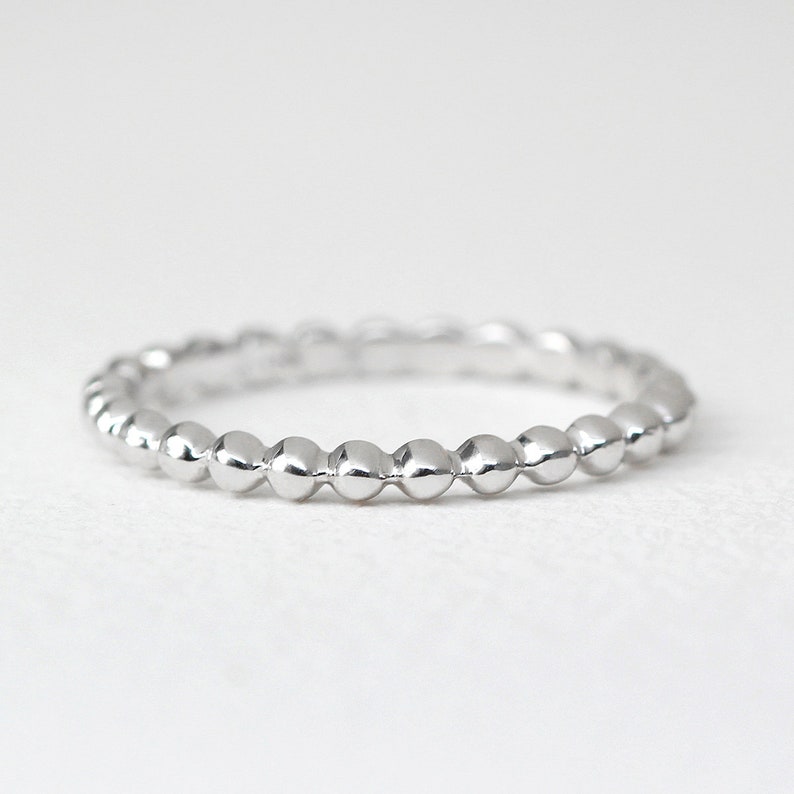 K&ouml;nnte beinhalten: Ein silberner Perlenring mit schlichtem Design. Der Ring besteht aus kleinen, runden Perlen, die gleichm&auml;&szlig;ig verteilt sind.