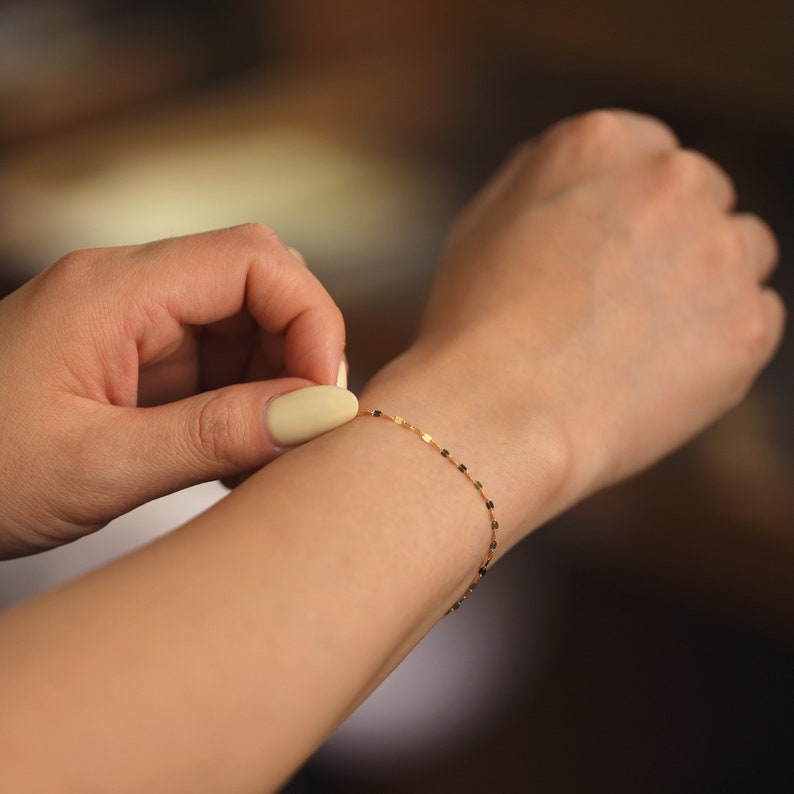 Puede incluir: Un delicado brazalete de cadena de oro con un dise&ntilde;o de eslabones cuadrados. El brazalete se lleva en la mu&ntilde;eca.