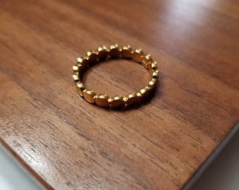 May include: A gold ring made of small, round beads.