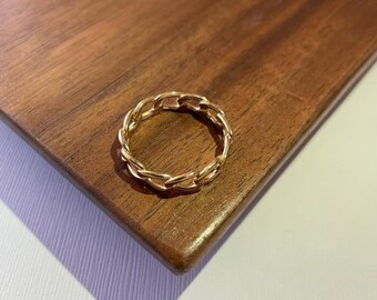 May include: A gold chain ring with a thick, chunky design. The ring is made of metal and has a polished finish.