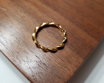 May include: A gold-toned ring with a twisted design. The ring is made of metal and has a smooth finish.