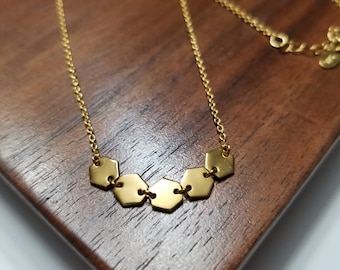 May include: A gold necklace with a chain and a pendant made of six connected hexagonal shapes.