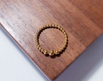 May include: A gold beaded ring with three larger beads in the center.