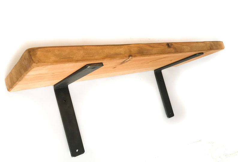 K&ouml;nnte beinhalten: Ein Holzregal mit nat&uuml;rlicher Holzoptik und zwei schwarzen Metallkonsolen. Das Regal besteht aus einem einzigen St&uuml;ck Holz mit einer lebenden Kante.