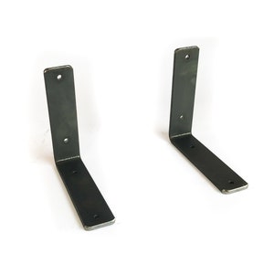 K&ouml;nnte beinhalten: Zwei schwarze Metall-Regalhalterungen mit einem 90-Grad-Winkel. Die Halterungen sind aus robustem Metall gefertigt und haben eine rustikale Oberfl&auml;che.