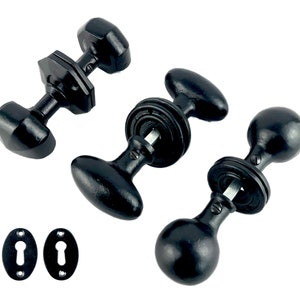 May include: Three black door knobs in different styles. The knobs are made of metal and have a matte finish. The knobs are shown against a white background.