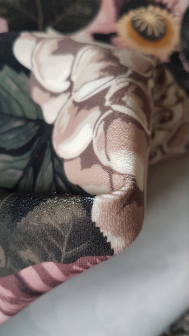 May include: Close-up of a fabric with a floral pattern. The fabric is a mix of pink, brown, and green colors. The fabric has a soft, velvety texture.