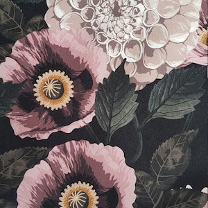 May include: A black fabric with a floral pattern featuring pink poppies and white dahlias. The flowers are surrounded by dark green leaves.