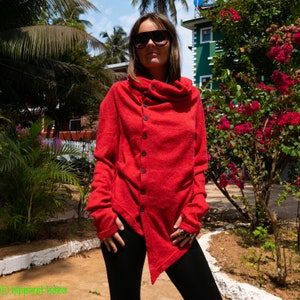 May include: A red, long-sleeved, asymmetrical cardigan with a high collar and a single button closure. The cardigan is made of a soft, knit fabric.