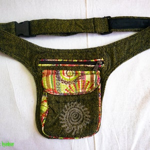 Puede incluir: Una riñonera de lona verde con un bolsillo con cremallera y un forro de tela estampado de colores. El bolsillo tiene una cremallera y un diseño de sol decorativo.