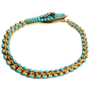 Könnte beinhalten: Ein schlangenförmiges Armband aus Gold mit einem durchgehenden Muster aus kleinen, runden, hellblauen Türkis-Cabochons. Der Schlangenkopf ist mit einem roten Edelsteinauge und kleinen weißen Akzentsteinen auf dem Kopf verziert.
