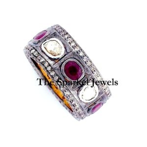 May include: A silver band ring with a row of alternating red and white gemstones. The ring is set with small diamonds around the gemstones.