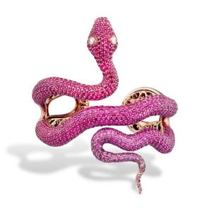 Può includere: Un bracciale a forma di serpente in oro rosa, caratterizzato da un'incastonatura a pavé di numerose piccole pietre rosa brillante che coprono l'intera superficie. La testa del serpente presenta due piccole pietre rotonde e chiare come occhi.