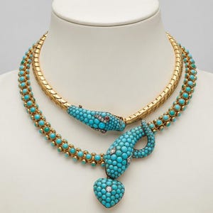 May include: A gold snake necklace featuring a textured metal band and a flexible chain adorned with numerous small, round turquoise beads. The snake head and tail are encrusted with turquoise, small diamonds, and red stone accents.
