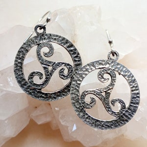 Pode incluir: Brincos de prata com acabamento martelado e design de nó celta.