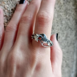May include: A silver ring with a vine design and two leaves. One leaf is silver and the other is gold.