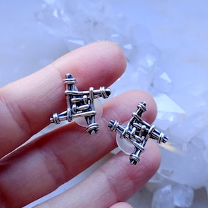 Pode incluir: Um par de brincos de prata com um design tecido em forma de estrela de quatro pontas.