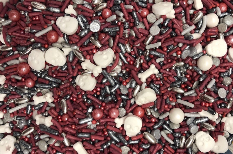 May include: A mix of red, white and silver sprinkles, including skull and bone shapes, ideal for decorating cakes and cupcakes.