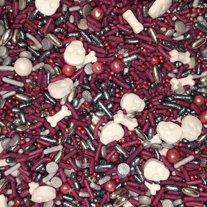 May include: A mix of red, silver, and white sprinkles. The sprinkles are shaped like skulls, bones, and small balls.