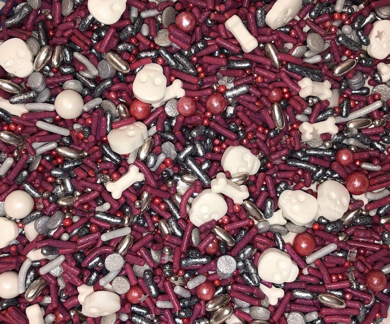 May include: A mix of red, silver, and white sprinkles. The sprinkles are shaped like skulls, bones, and small balls.