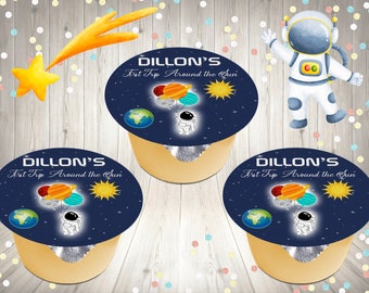 May include: Three round labels with a blue background and a white astronaut holding balloons with planets. The text on the labels reads "DILLON'S First Trip Around the Sun".