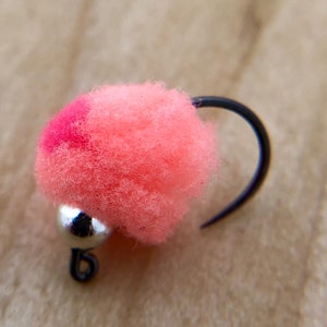 May include: A pink and red fly tying material with a silver bead and black hook.