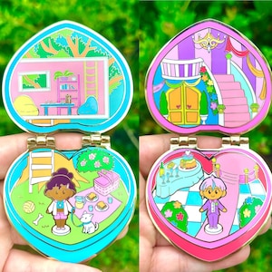 Peut inclure: Quatre broches émaillées articulées en forme de cœur avec une bordure dorée. Chaque broche présente une scène intérieure différente : un salon, un château, un pique-nique et une fête. Les broches sont dans diverses nuances de rose, bleu, vert et or.