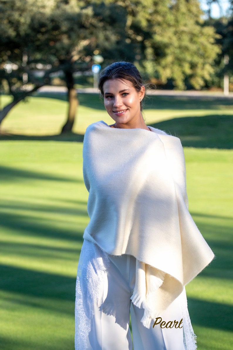 Young and pretty bride wrapped into a warm alpaca shawl at an outdoor wedding ceremony